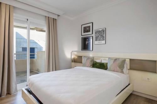 1 dormitorio con 1 cama blanca grande y ventana en Apartamento Puerto Banús con Parking & piscina., en Marbella