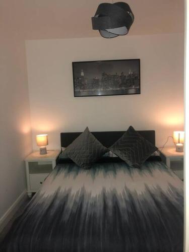 a bedroom with a bed with two tables and two lamps at Luxurious Seaside Apartment in Bangor