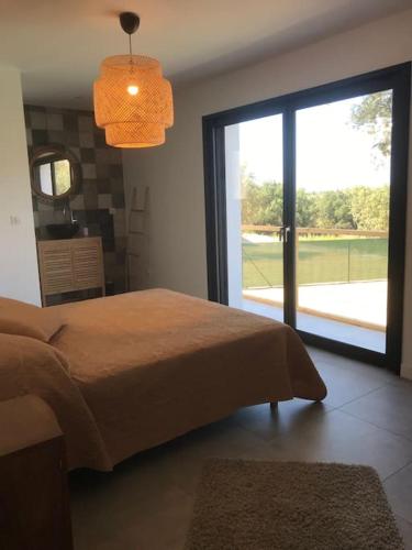 - une chambre avec un lit et une grande porte coulissante en verre dans l'établissement Villa Rossa Contemporaine Piscine chauffée, à Palasca