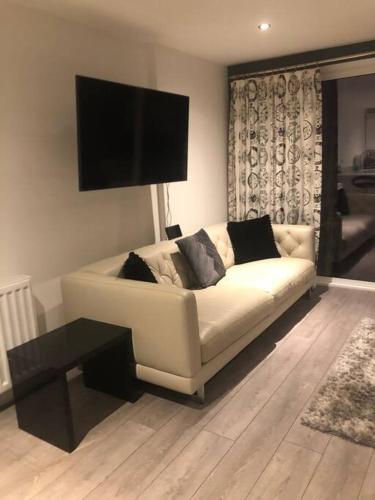 a living room with a white couch and a flat screen tv at Luxurious Seaside Apartment in Bangor