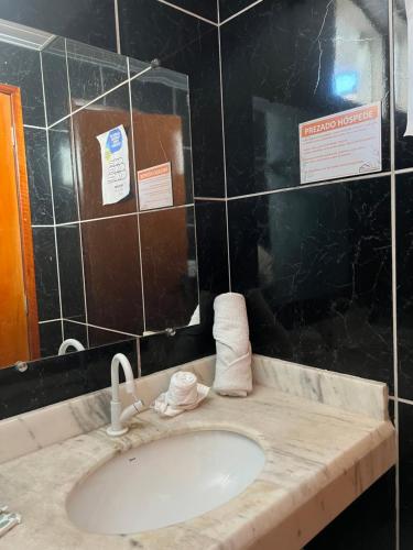 a bathroom with a sink and a black tiled wall at Pousada Papaya - Bonito in Bonito