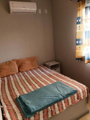 a bedroom with a bed with a blanket on it at Jardim das orquideas 2 in Rio das Ostras