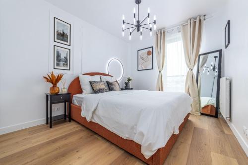 Un dormitorio con una cama grande y una lámpara de araña. en Appartement en face gare d'Evry - Proche Paris & Disney - Easy check in - Arrivée autonome -Place de parking privative - Wifi, en Évry-les-Châteaux