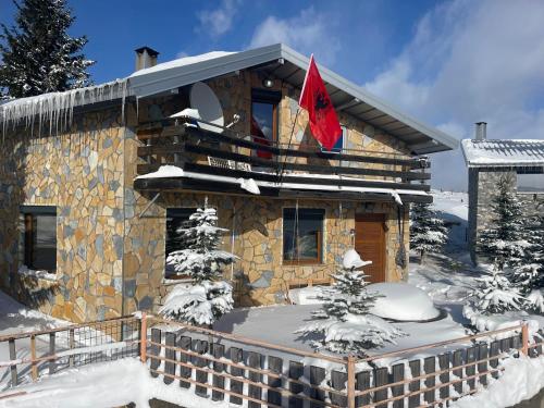 a building with a red flag on it in the snow at Villa 80 Kodra e Diellit in Tetovo