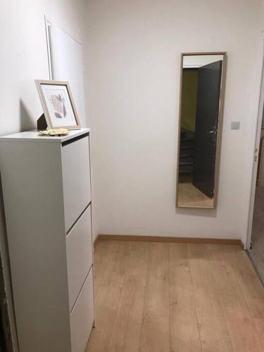 Dieses weiße Zimmer verfügt über einen Spiegel und eine Kommode. in der Unterkunft Appartement entier 2 chambres longwy in Longwy