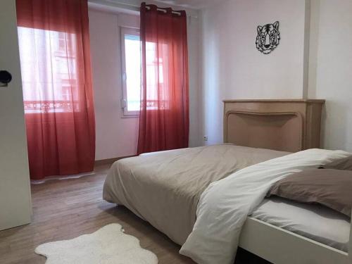 Schlafzimmer mit einem Bett, roten Vorhängen und einem Fenster in der Unterkunft Appartement entier 2 chambres longwy in Longwy
