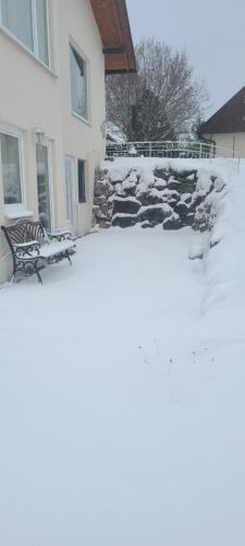 a snow covered yard with chairs and a house at Ferienwohnung Haus Graf in Irdning