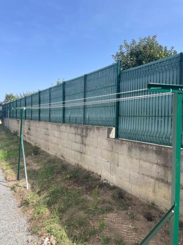 una recinzione verde su un muro accanto a una strada di Chez Olivier et Damien a La Roche-sur-Yon