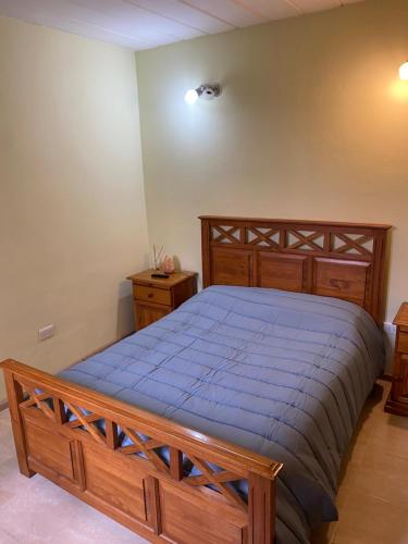 a bedroom with a large wooden bed with blue sheets at Dptos RT in Yacimiento Río Turbio