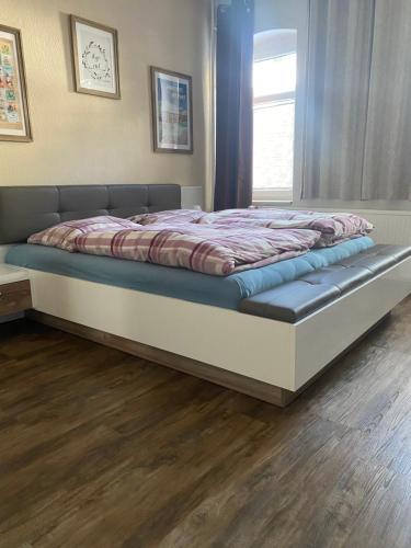 ein großes Bett in einem Schlafzimmer mit Holzboden in der Unterkunft Das Rübezahl in Bad Elster