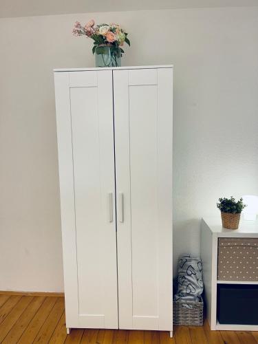 a white cabinet with a vase on top of it at Vintage Apartment Nuremberg Old Town in Nuremberg