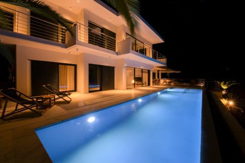 a swimming pool in front of a house at night at Villa Kilada on the Rocks in Kilada