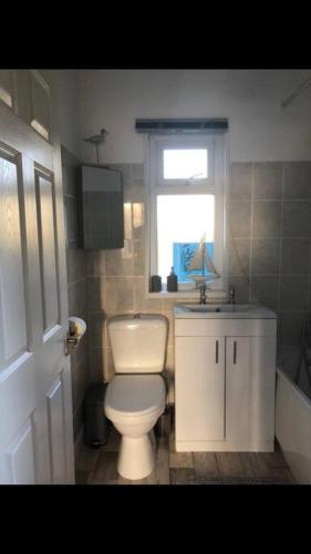 a bathroom with a toilet and a sink and a window at Cosy Seaside Home in Groomsport