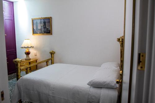 a bedroom with a white bed and a lamp at Casa Zepeda in Atlixco