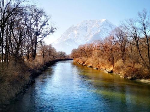 a river with a snow covered mountain in the background at Ferienwohnung Haus Graf in Irdning