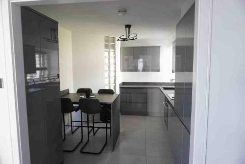una cucina con mobili neri, tavolo e sedie di LUXURIOUS SEASIDE APARTMENT a Groomsport