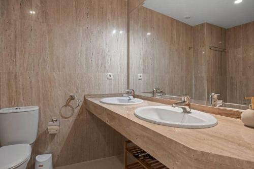 uma casa de banho com 2 lavatórios e um WC em Luminoso apartamento en Elviria em Marbella