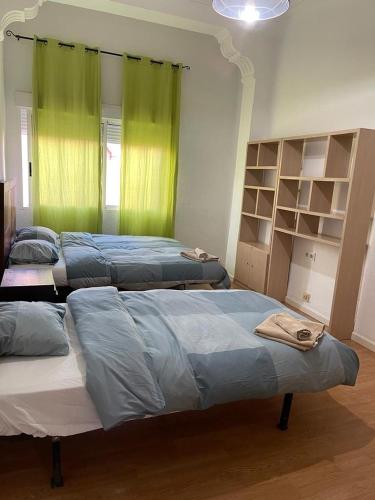 two beds in a room with green curtains at UIM Mediterraneo Pablo Iglesias Wifi in Puerto de Sagunto