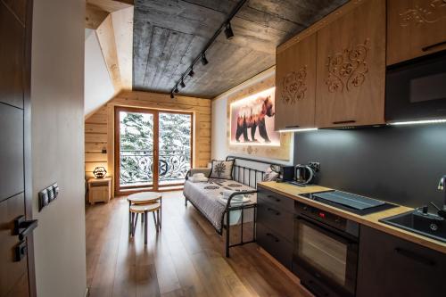 a kitchen and living room with a couch and a table at Cyrhel Apartments in Zawoja