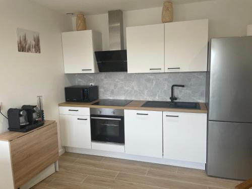 a kitchen with white cabinets and a stainless steel refrigerator at Studio cozy 30m² près RER/CDG/Parc des Expos in Villepinte