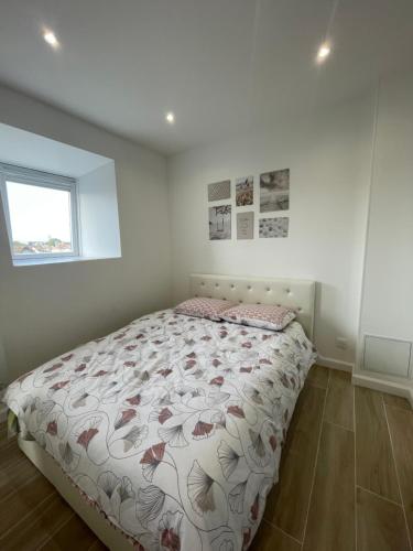 a bedroom with a bed with a floral comforter at Studio cozy 30m² près RER/CDG/Parc des Expos in Villepinte