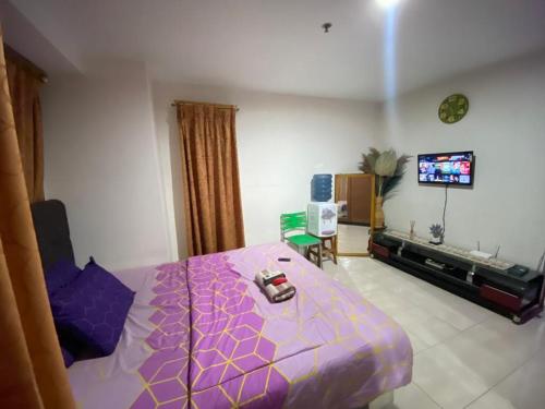 una camera con letto viola e TV a schermo piatto di VR APARTMENT a Kemirimuka Dua