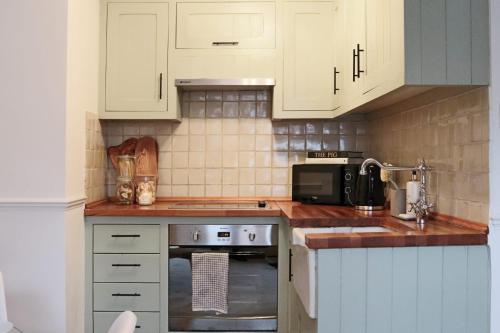 a kitchen with white cabinets and a stove and a microwave at Japandi-Inspired Apt in the Heart of Oxford in Oxford