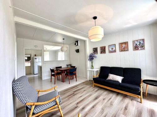 - un salon avec un canapé et une salle à manger dans l'établissement Kioloa Beach Cabins, à Kioloa
