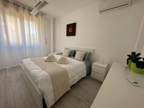 a white bedroom with a large bed with towels on it at Appartamento Su Planu IUN R5007 in Pirri