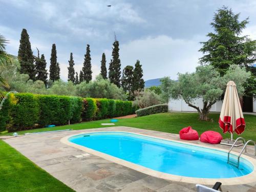a swimming pool in a yard with an umbrella at Luxurious 6 bedroom villa In a great location in Chalkida
