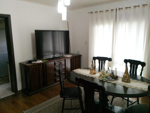 een eetkamer met een tafel met stoelen en een televisie bij Casa aconchegante Gramado em local tranquilo- 5 km do centro locação temporada in Gramado