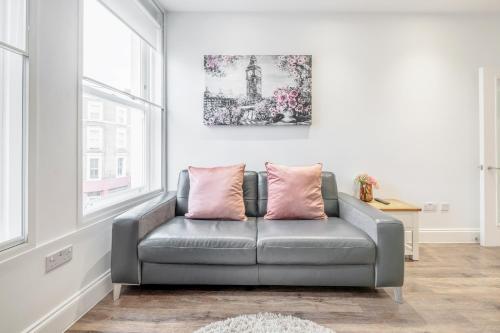 a grey couch in a room with a window at Bright & Modern 2-Bed Notting Hill Apartment in London