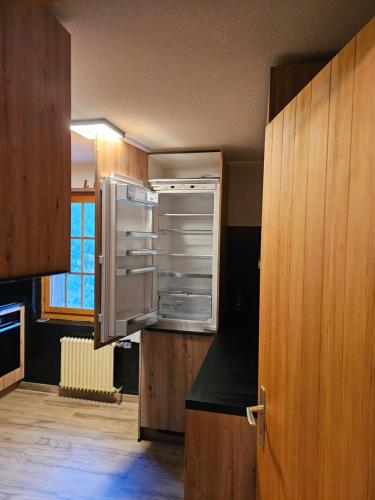 una cocina con una nevera vacía en una habitación en Le Panorama - Appartement 54 à Arolla face aux montagnes à 150m des pistes, en Evolène