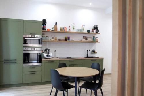 Una cocina con gabinetes verdes y una mesa y sillas. en La Casa di Gadu, en Casalnuovo di Napoli