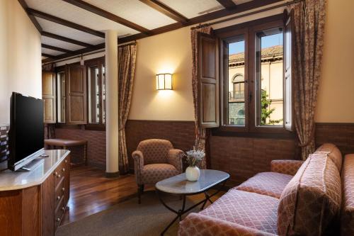a living room with a couch and a tv at Hotel Palacio de Santa Paula, Autograph Collection in Granada