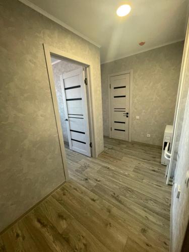 Habitación vacía con 2 puertas y suelo de madera. en 1-КОМНАТНАЯ КВАРТИРА ЕВРО В НОВОСТРОЙКЕ en Petropavlovsk