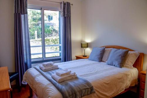- une chambre avec un grand lit et des serviettes dans l'établissement Tranquility Apartment, à Caniço