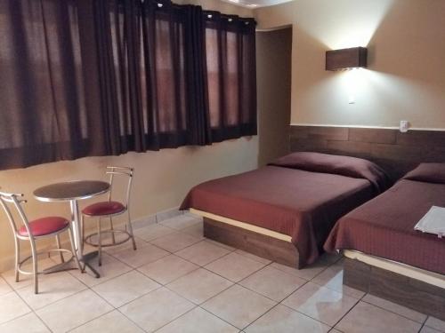 um quarto com 2 camas, uma mesa e cadeiras em Hotel Costa Miramar Acapulco em Acapulco