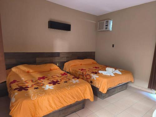 two beds in a room with orange comforter at Hotel Delfines Del Mar in Acapulco