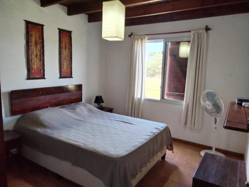 1 dormitorio con 1 cama, ventana y ventilador en Casa Nuestro Sueño en Punta del Diablo