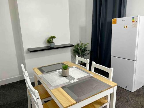 a table and chairs with a white refrigerator in a room at Home In Medway in Chatham