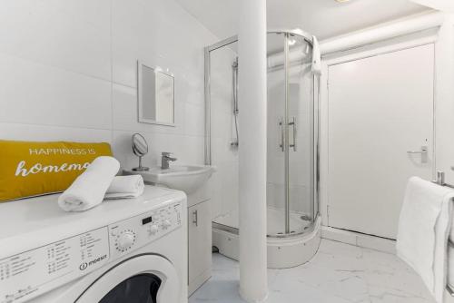 倫敦的住宿－Deluxe Studio Near Camden Town，白色的浴室设有洗衣机和水槽。