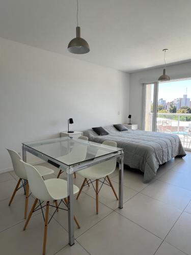 a bedroom with a bed and a glass table and chairs at D25 DIAGONAL in Neuquén