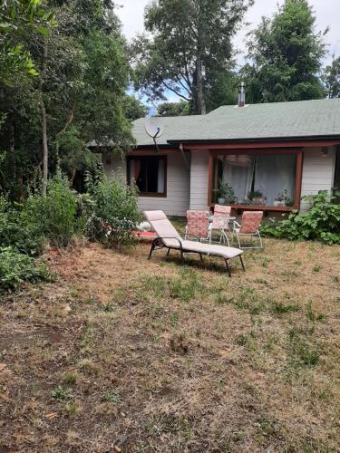 a house with two chairs and a bench in the yard at Cabañas Welcome Pucón. in Pucón