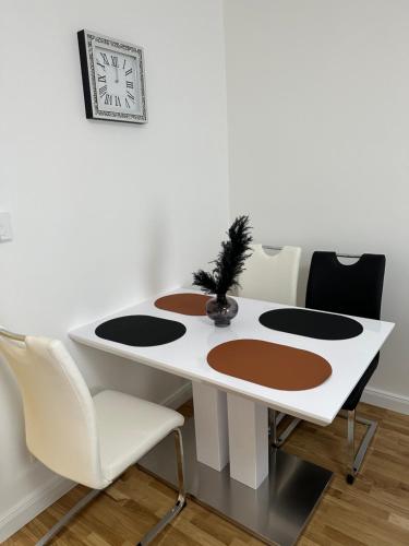 a white table with chairs and a clock on the wall at Gemütliche 2- Zimmer Apartment Nähe Neu Donau in Vienna