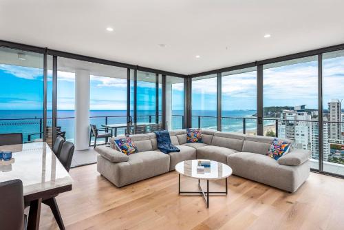 a living room with a couch and glass windows at Breathtaking Burleigh Beach Abode in Gold Coast