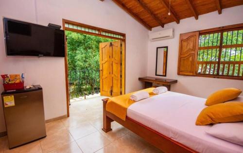 1 dormitorio con 1 cama, TV y ventana en Hotel San Sebastian del Tonusco en Santa Fe de Antioquia