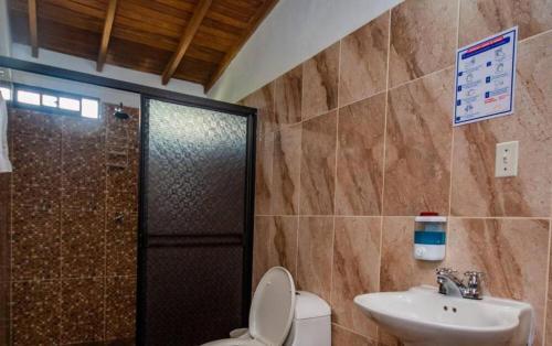 y baño con aseo, lavabo y ducha. en Hotel San Sebastian del Tonusco en Santa Fe de Antioquia