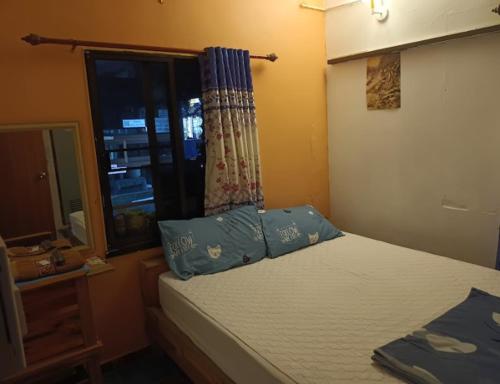 una camera da letto con un letto con cuscini blu e una finestra di หอพักบ้านชูใจ a Phitsanulok