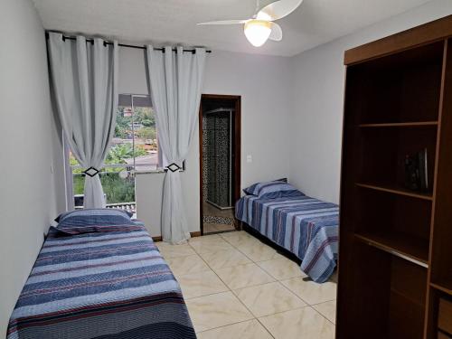 um quarto com 2 camas e uma janela com cortinas em Casa aconchego Parque Mambucaba em Angra dos Reis